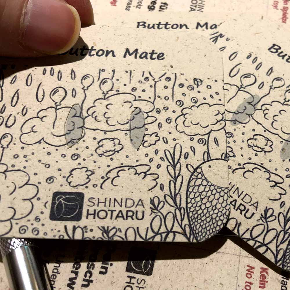 Nahaufnahme der Rückkarte (Backing Card) der Buttons, bevor die Löcher für die Button-Nadel ausgeschnitten wurden.